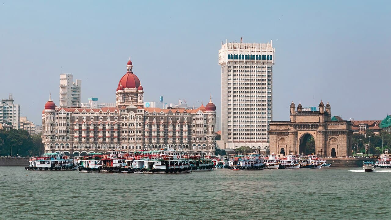 Panoramic view of Taj Palace Hotel and Taj Tower with the iconic Gateway of India in the background, overlooking the Arabian Sea in Mumbai